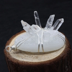 Macro view of handmade silver wire wrapped natural clear crystal quartz pendant on wood