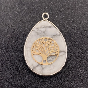 Macro detail of teardrop white stone pendant with gold tree of life metal inlay