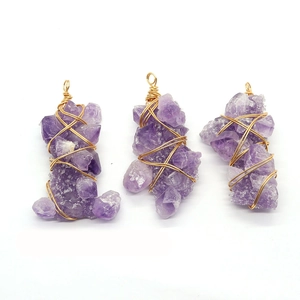 Three natural purple amethyst raw stone pendants wrapped in golden wire on white background