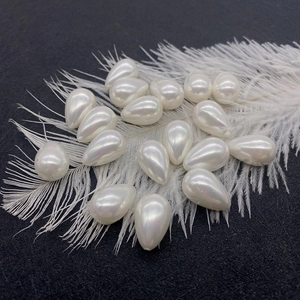 Waterdrop-shaped cream faux pearl beads for DIY jewelry making on white feather background