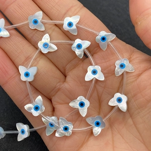 Makro-Detail von weißen Schmetterlingsperlen aus Muschel mit blauem Auge-Muster