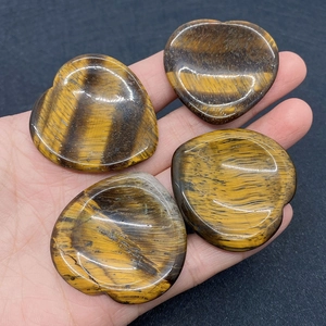 Polished heart-shaped tiger eye stones with natural golden brown cat-eye texture in hand