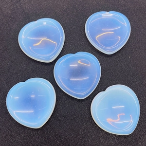Macro detail of five heart-shaped opalite stones on a textured black background