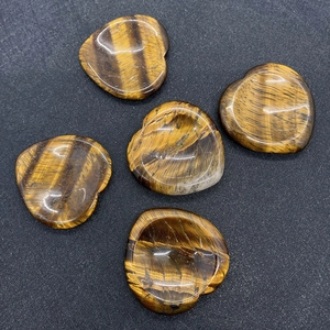 Macro view of five polished heart-shaped tiger eye stones with golden silk luster