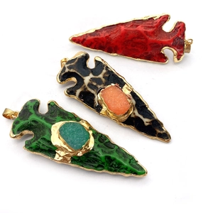 Détail de trois pendentifs coniques en résine avec bords dorés et pierres naturelles