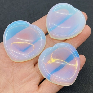 Close-up of heart-shaped opal thumb stones with iridescent blue and white glow