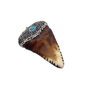 Dettaglio di ciondolo in resina a forma di corno con strass e pietra di turchese