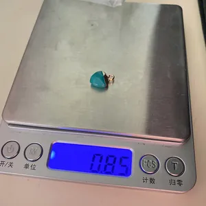 Macro detail showing a heart-shaped turquoise stone pendant on a digital scale weighing 0.85g