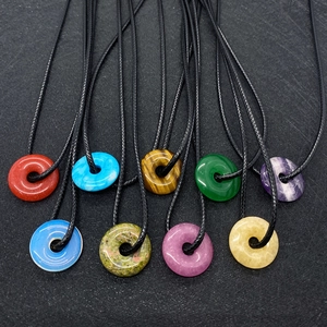 Vue à plat de pendentifs donuts en pierres naturelles avec cordons noirs sur fond sombre