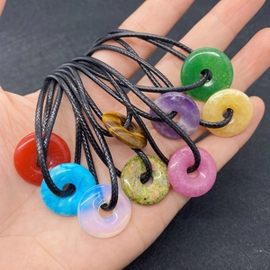 Close-up of assorted 20mm natural stone donut pendants with black cord necklaces