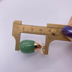Detail view of a green teardrop stone pendant measured with a caliper showing 26mm size