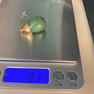 Macro shot of a green aventurine teardrop pendant on a scale weighing 8.11 grams