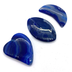Dettaglio macro di ciondoli in agata blu con forme a cuore e luna per gioielli