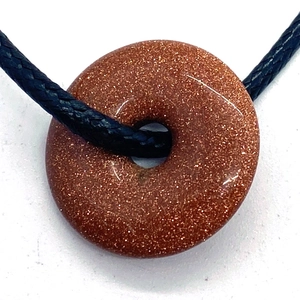 Natural brown goldstone donut pendant necklace with black woven cord on white background