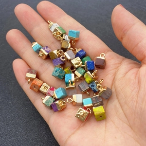 Mix of colorful cubic natural stone pendants with gold plated rings held in hand