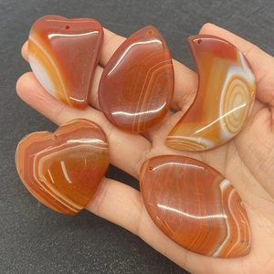 Close-up of red agate pendants in various shapes including heart and teardrop for DIY jewelry
