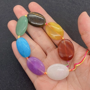 Macro detail of oval semi-precious gemstones handwoven on a rainbow braided cord