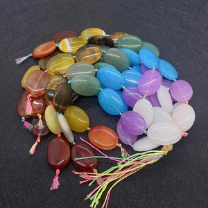 Detail view of smooth oval natural stone beads in mixed colors with tassels