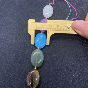 Macro view of 15mm oval semi-precious stone beads measured with a brass caliper