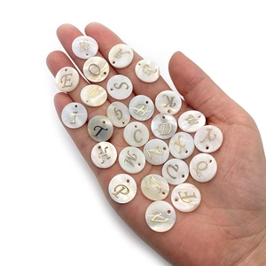 Vue détaillée des perles en nacre de 15mm avec gravure dorée de l'alphabet