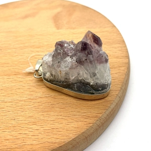 Ciondolo a fetta di geode di ametista viola naturale con bordo in metallo argentato su legno