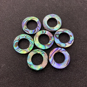 Close-up of seven natural abalone shell ring charms with vibrant iridescent luster
