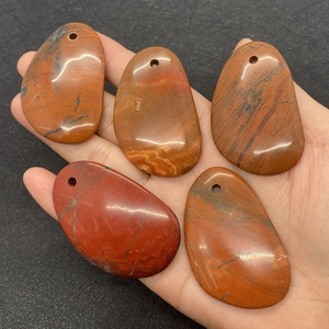 Dettaglio di cinque ciondoli in agata naturale irregolare con finitura rosso scuro