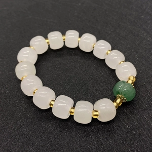 Bracciale di perle di giada bianca naturale con pietra verde e accenti dorati su sfondo nero