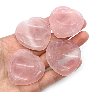 Detalle de cuatro piedras de preocupación de cuarzo rosa en forma de corazón en mano