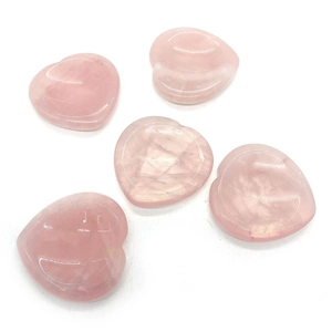 Detalle de cinco piedras de pulgar de cuarzo rosa en forma de corazón pulidas