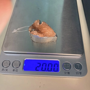 Detailopname van een hanger van natuursteen op een weegschaal met 20 gram gewicht