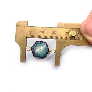 Vue macro d'un pendentif en pierre hexagonale de 14mm mesuré avec un pied à coulisse