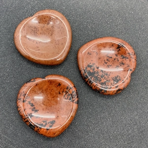 Macro-detail van drie hartvormige mahonie obsidiaan duimstenen met glad gepolijst oppervlak