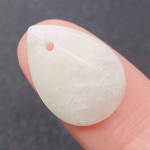 Macro shot of polished teardrop Burmese jade pendant with natural translucent texture
