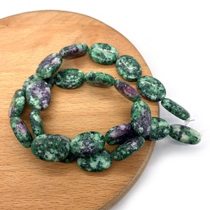 Vista dettagliata di perle ovali in rubino-zoisite 13x18mm su vassoio in legno per gioielli