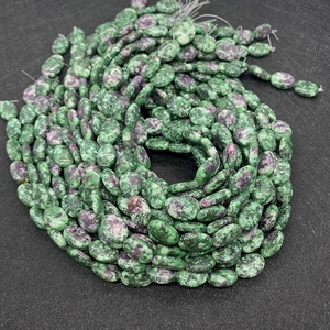 Dettaglio di perle ovali in rubino zoite lucido per creazione di gioielli fai da te