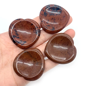 Hartvormige Mahogany Obsidian duimstenen voor massage vastgehouden in de hand