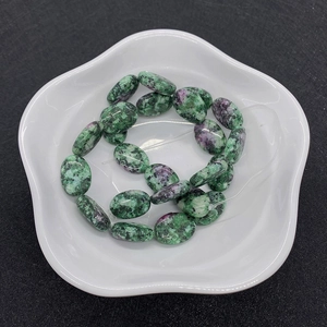 Dettaglio di perline ovali in rubino naturale su zoisite su un piatto di ceramica bianca
