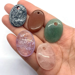 Macro shot of five natural gemstone oval pendants held by hand for DIY jewelry making
