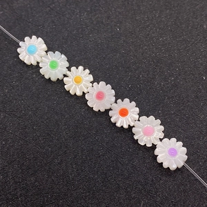 Macro detail of natural shell daisy beads with colorful drip oil centers for DIY jewelry making