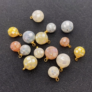 Macro shot of natural shell mosaic beads in assorted colors with gold rings for DIY jewelry