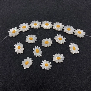 Dettaglio macro di perline a margherita 10x12mm con petali iridescenti e centri gialli