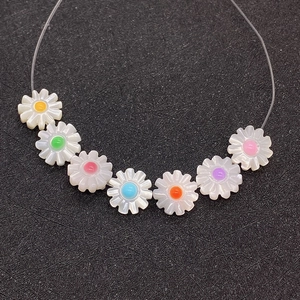 Detail view of seven small daisy shell beads with colorful centers for jewelry making