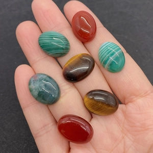 Sélection de pierres précieuses ovales en œil de tigre et agate rouge tenues en main