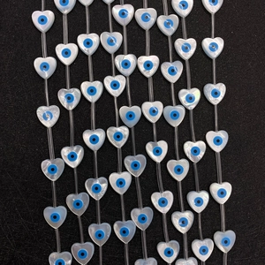 Macro shot of heart-shaped sea shell evil eye beads with blue center on black texture