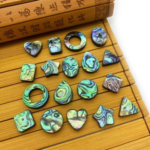 Assorted natural abalone shell geometric charms with iridescent luster on bamboo mat