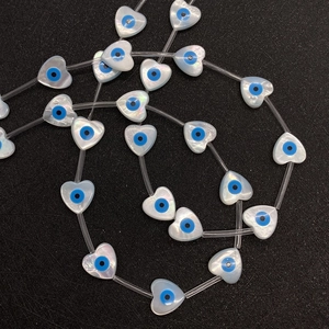 Macro shot of heart-shaped evil eye shell beads with iridescent mother of pearl texture