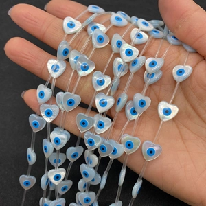 Macro detail of heart-shaped natural shell beads with evil eye pattern for DIY jewelry