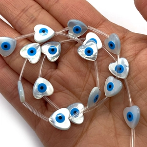 Handheld view of heart-shaped natural mother of pearl evil eye beads for DIY jewelry