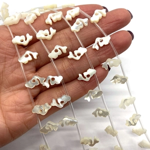 Makroaufnahme natürlicher weißer Perlmuttperlen in Fischform für DIY-Schmuck